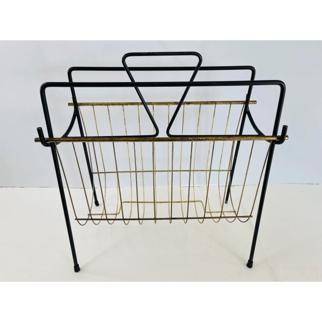 Vintage 1950s black and gold metal magazine rack. Has two sections for magazines. No marks.