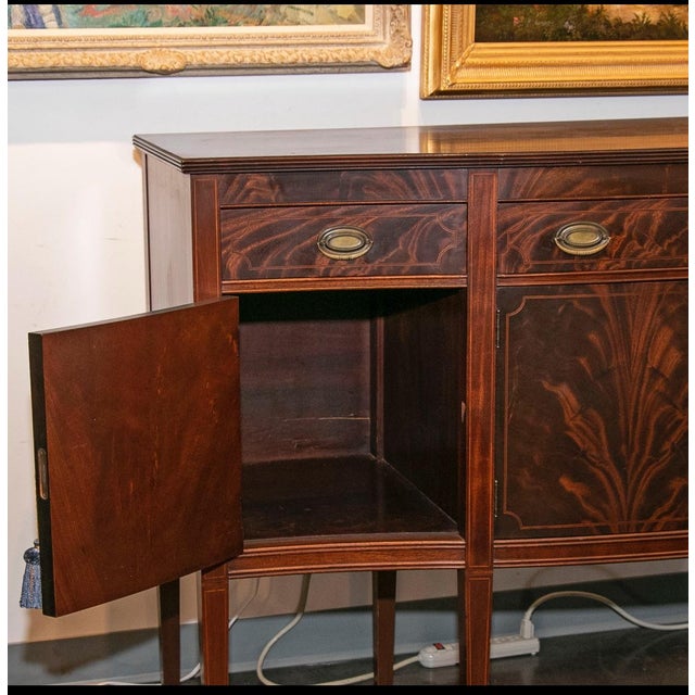 Dated to the early 1900s, this antique sideboard by Williams-Kimp Furniture exhibits beautiful eye catching inlaid flame...