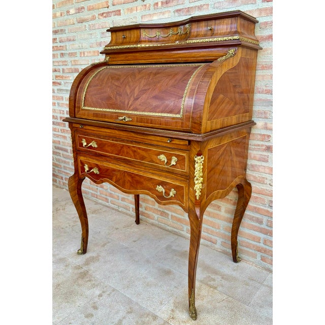 Elegant French bureau, featuring fine marquetry decoration and richly detailed gilt-bronze mounts. The curved upper...
