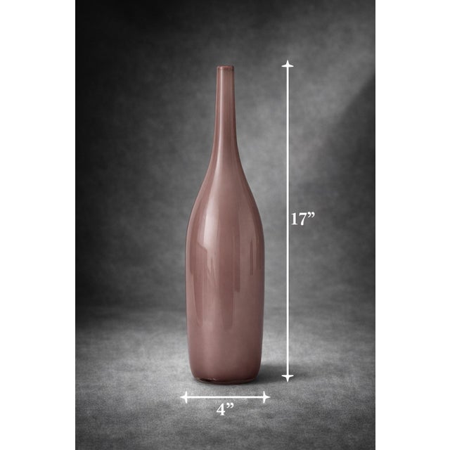 Elegant blush mauve art glass bud vase featuring a tall, slender bottle form and softly translucent finish. Its minimalist...