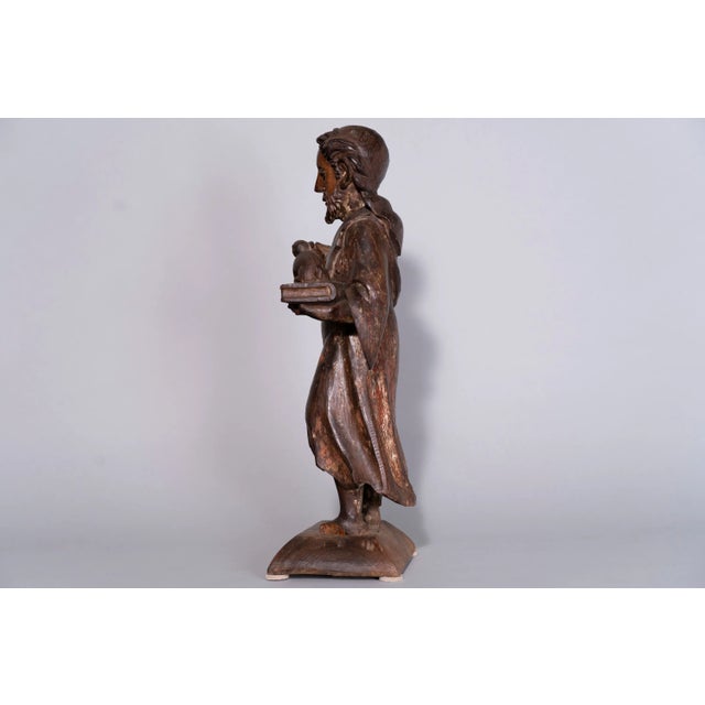 Circa 17th Century French Wooden Saint John the Baptist. Exceptionally hand-carved, this Saint holds a lamb and a bible in...