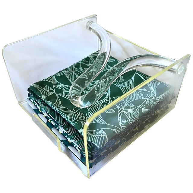 A stylish vintage Lucite cocktail napkin holder with a sculptural curved arm and a clean, transparent frame. Upright side...