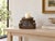 Look at the carving first. A single leaf rises from the center of each face, framed by tight scrolls at the corners and a...