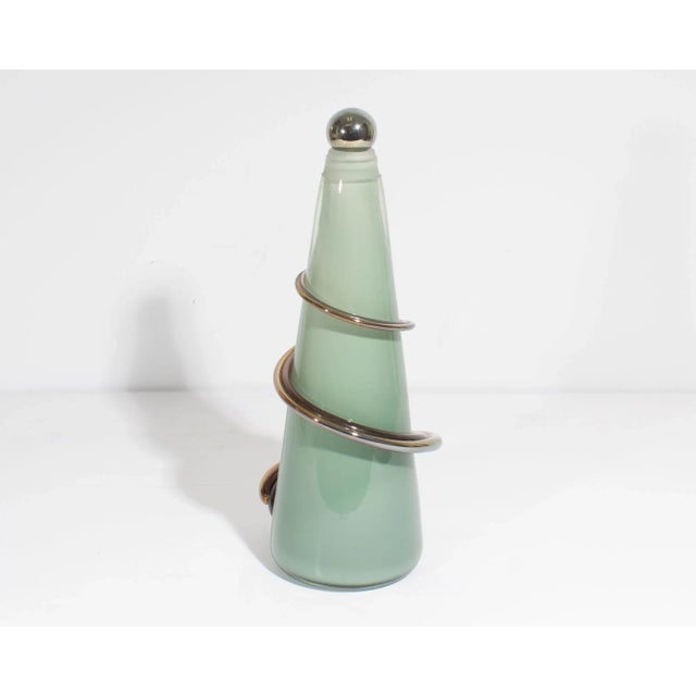 An art glass decanter or decorative bottle by the American glass artist Eric Bladholm. This piece has a conical body made...