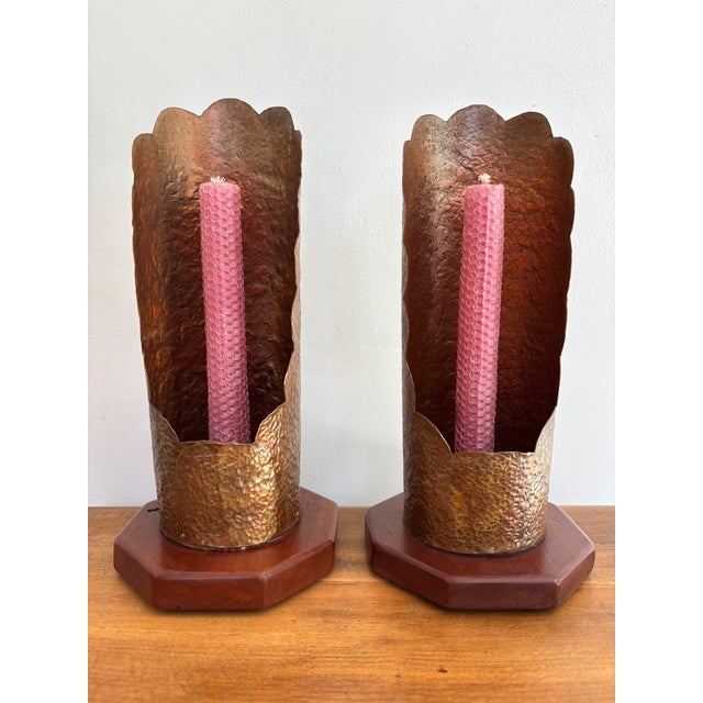 A matching pair of Arts & Crafts hammered copper candlestick holders on wood bases, hand-crafted in the mid 20th century....