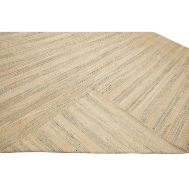 Beautiful kilim handmade wool rug with a beige field. This Modern flatweave rug has blue and brown accents and features a...