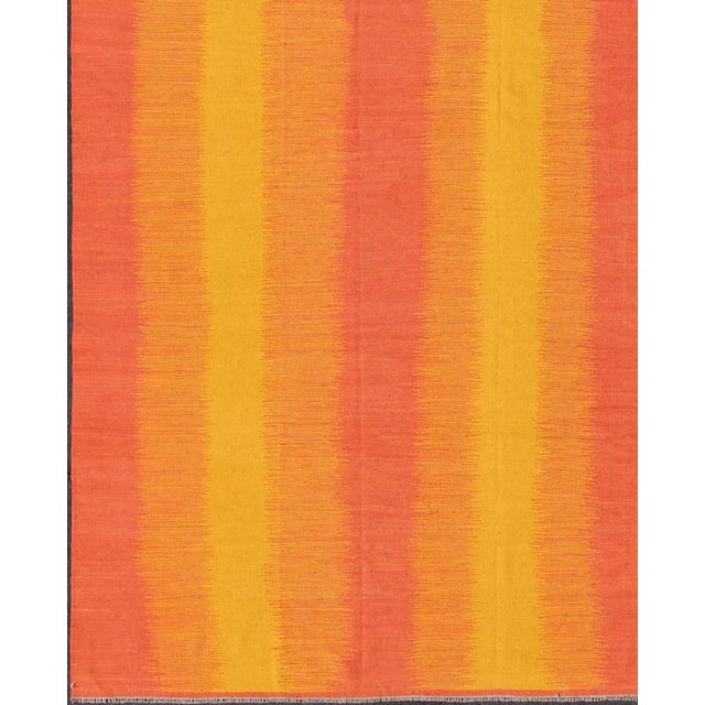 This gorgeously woven designer Kilim is decorated with a vertical stripe pattern. The flat-woven rug is rendered in shades...