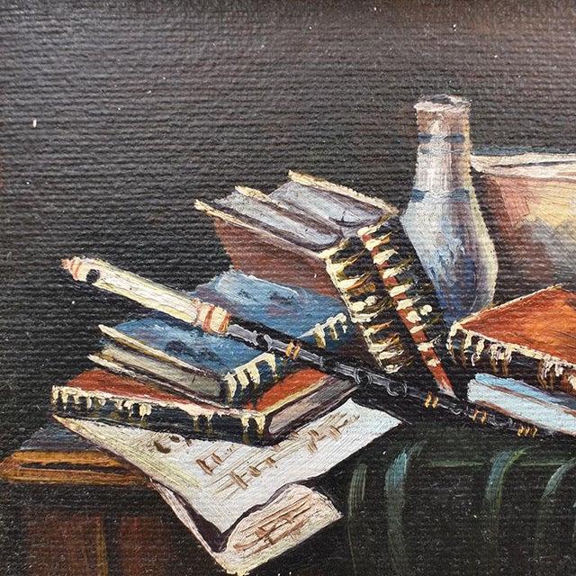 A traditional still-life painting of a variety of books. This pretty piece is framed in a gilt faux fern leaf frame with...