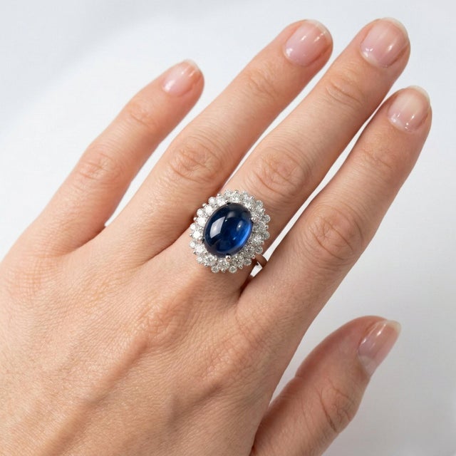 Elegant and timeless, this 14K white gold ring features an oval cabochon blue sapphire weighing approximately 4.76 carats,...
