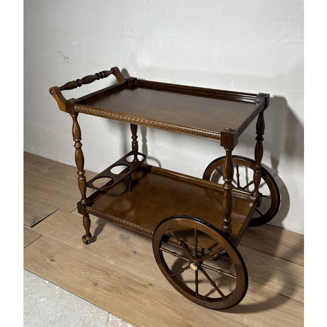 Elegant Spanish bar cart crafted in solid wood, featuring a classic two-tier design with finely turned legs and decorative...