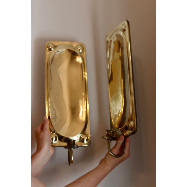 Made in Sweden. Two exquisite brass candle sconces from the Mid Century era, meticulously handcrafted with a stunning...