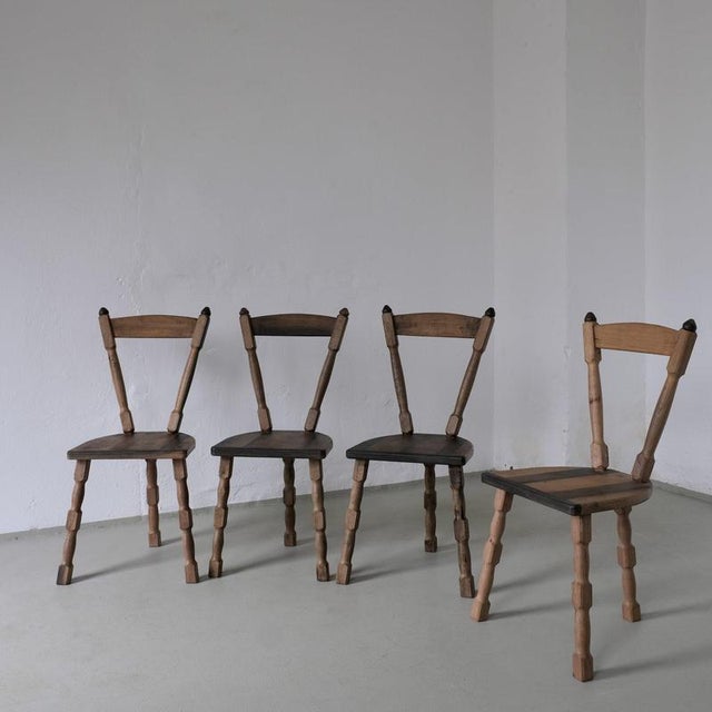 Set of four handcrafted dining chairs with a unique sculptural silhouette and turned wooden legs. Made from contrasting...