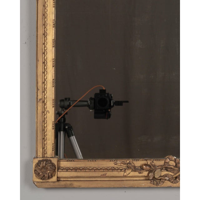 A Louis XVI style French giltwood mirror. Hand carved crest with large urn, torch, ribbons, and garlands. Gilt is in good...