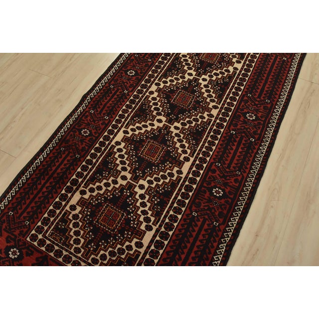 An authentic vintage tribal Baloch rug hand-knotted with fine wool and natural dyes. This nomadic oriental rug features a...