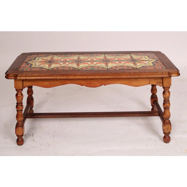 Spanish style oak coffee table with an inset tile top, circa 1930's. With an oak overhanging top with 10 colorful tiles, a...