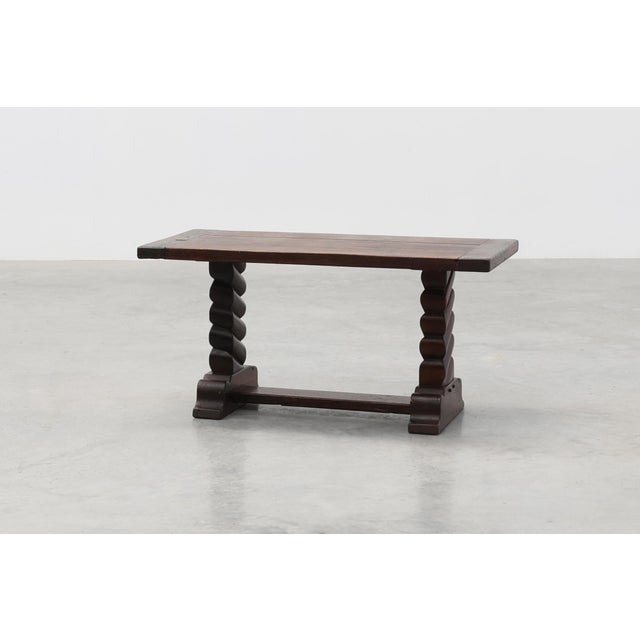 A handsome French coffee table from around 1915, crafted in solid dark oak with a rich, aged patina. The design features a...