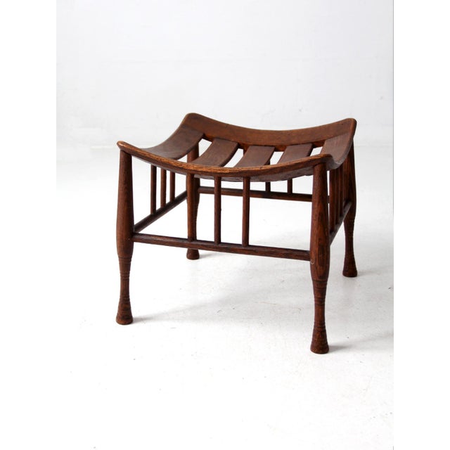 This antique Thebes stool showcases Egyptian Revival design with a curved slatted seat and splayed legs. Crafted from oak...