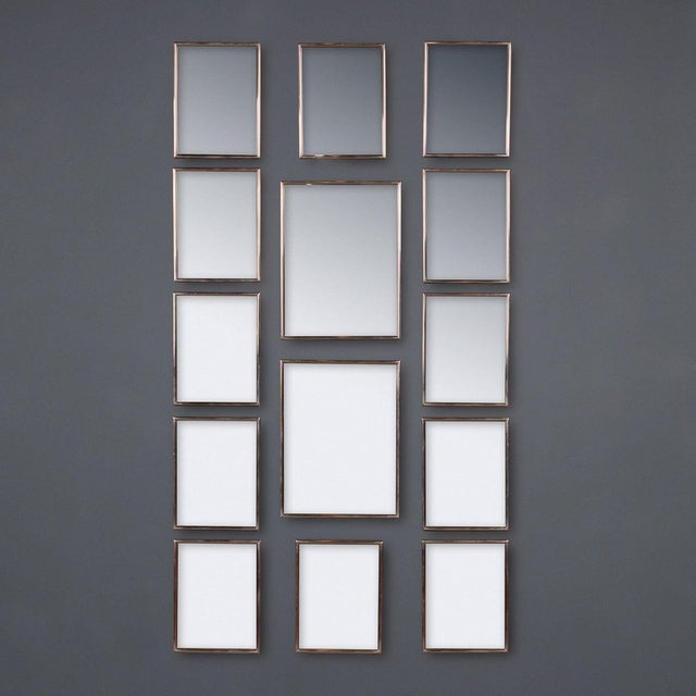 A vintage 20th Century Italian collection of fourteen mirrors, each set within silvered metal frames. The group offers a...