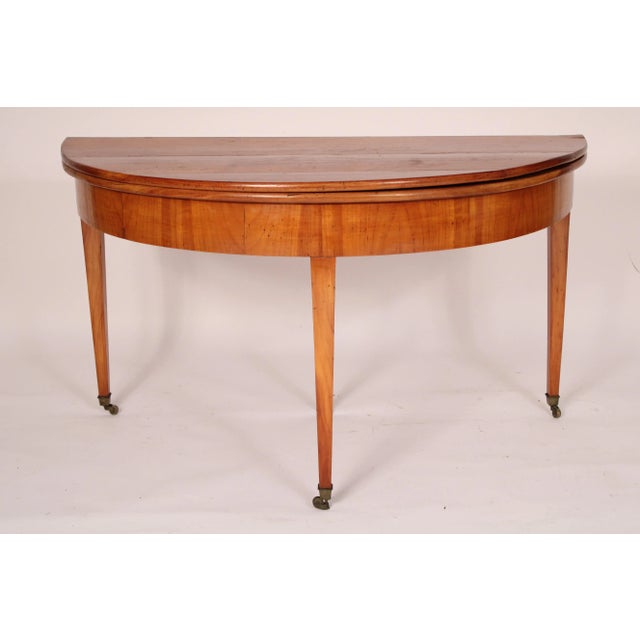 Continental Directoire fruit wood demi lune console / games table, early 19th century. Having a demi lune shaped top which...