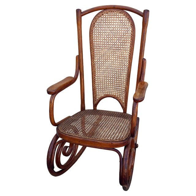 Vienna Secession style rocking chair featuring an elegant, sculptural frame crafted from warm-toned bentwood with striking...