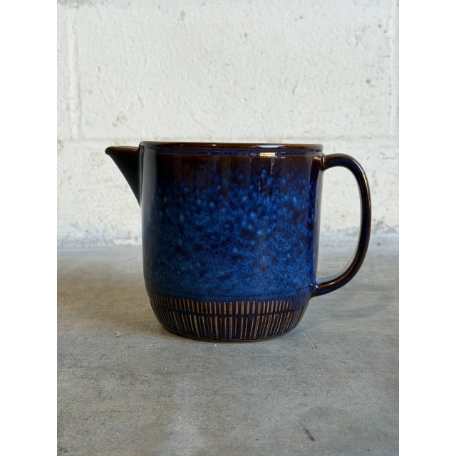 This vintage ceramic pitcher features a stout, cylindrical silhouette defined by a short, wide pouring spout and an...