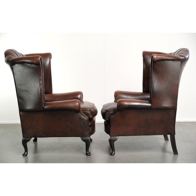 This charming set of 2 Chesterfield wingback armchairs is made of English-style cowhide leather. The armchairs feature a...