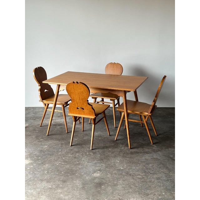 This vintage dining set pairs a rectangular oak table with four matching Stabelle chairs, both built on the same splayed,...