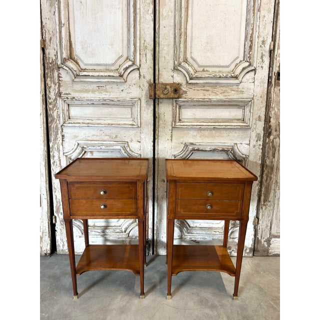 Pair of cherrywood bedside tables, circa 1970. The fronts open to reveal two drawers and a shelf forming a stretcher....