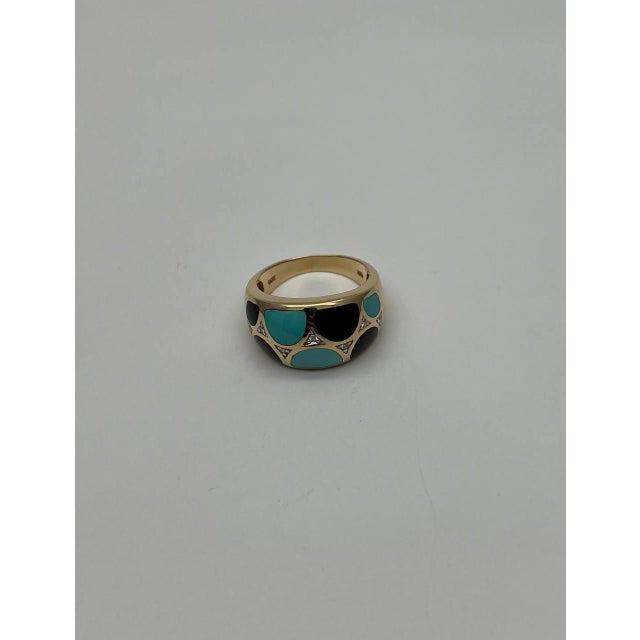 A striking ring featuring a bold design with turquoise and black onyx inlays set in a polished gold band. Intricate...