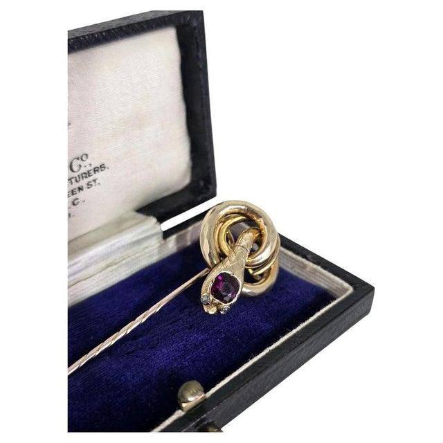 A Victorian 9ct yellow gold novelty stickpin modelled as a coiled serpent. The serpent's head is set with a cushion-cut...