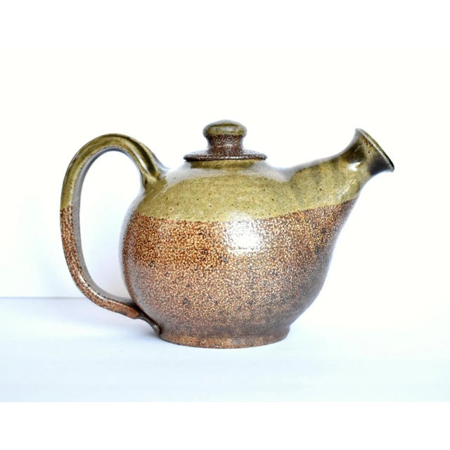 A vintage studio or art pottery stoneware teapot with a light moss green-tan and brown-tan speckled salt glaze, in an...