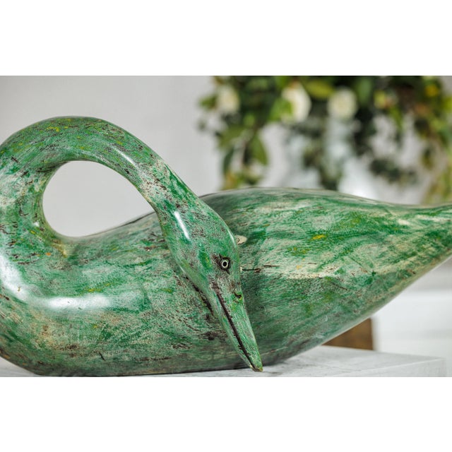 A vintage carved wooden swan distinguished by its gracefully curved neck and stylized form. The bird’s elongated body and...