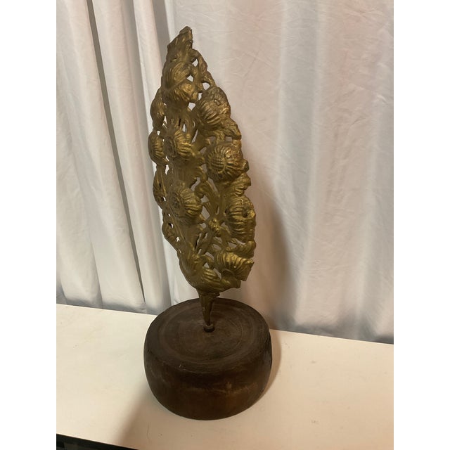 Antique European repoussé brass decorative sconce backplate with floral motifs, displayed on a wooden stand. Ornate brass...