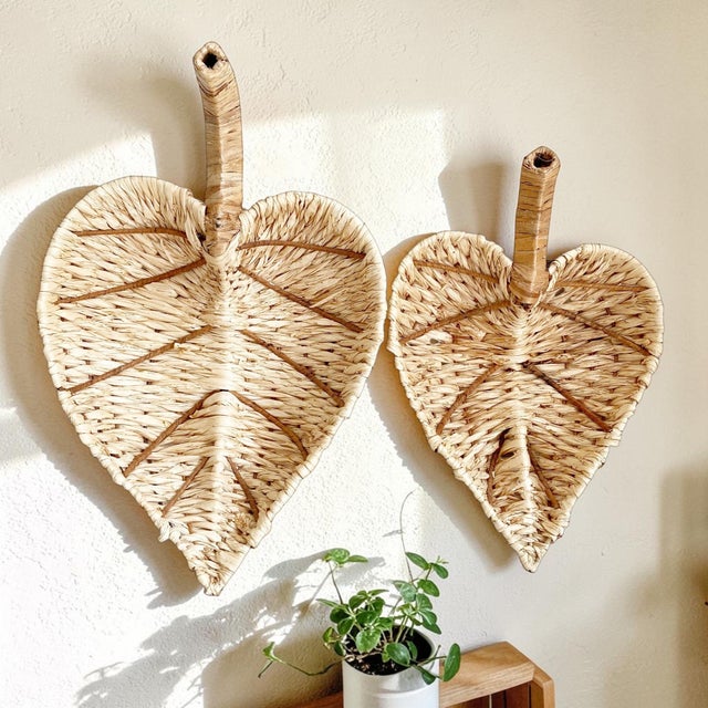 Elevate your home decor with this exquisite set of two Woven Leaf Baskets, perfect for both wall display and tabletop use....