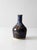 A vintage 1970s handmade studio pottery bud vase with a rounded bottle form and flowing blue and earthy brown glazes. The...