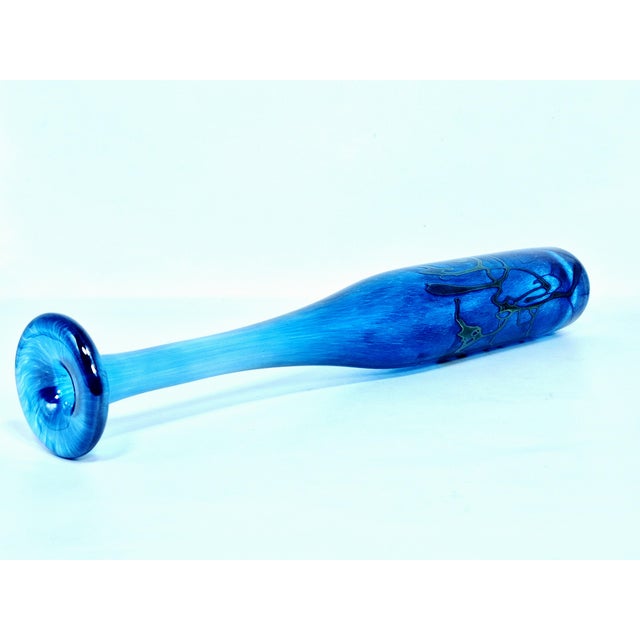 Tall, slender blue glass vessel is a hand-blown iridescent art glass bud vase, created by the renowned Canadian glass...