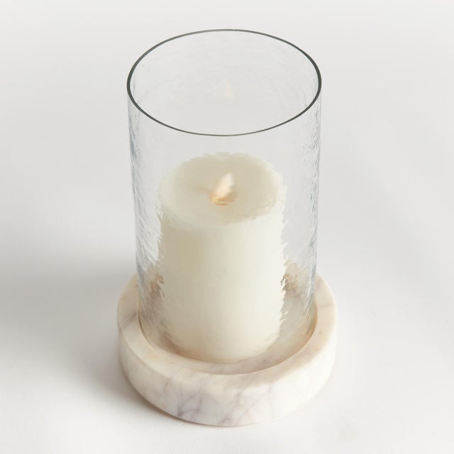With a hammered glass vessel that sits inside a simply marble tray, this hurricane is decidedly modern. The hammered glass...
