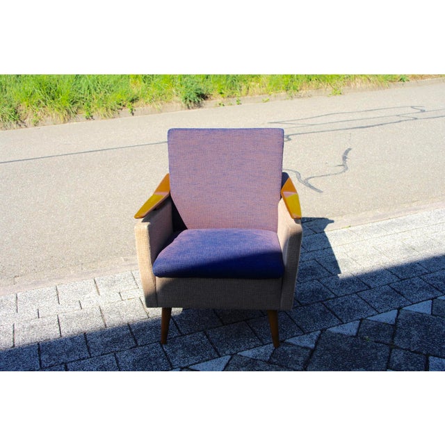 Wooden and fabric armchair from the 1960s with a boomerang-shaped suspended armrest in good condition This piece is...