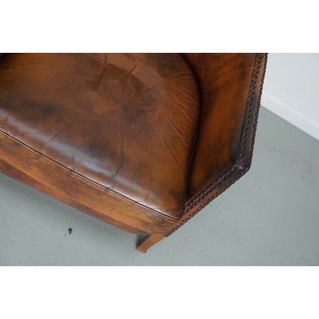 This pair of cognac-colored leather club chairs come from the Netherlands. They are upholstered with patinated cognac-...