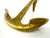 A sculptural mid-century brass candlestick formed as a stylized nautical anchor, balancing functional design with bold...