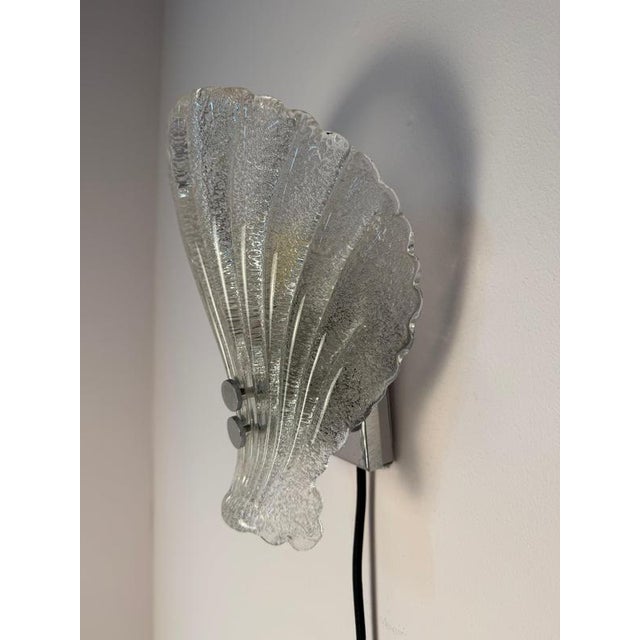 A sparkling eye-catcher in the style of the 1960s: This elegant, shell-shaped wall lamp was crafted by the renowned German...
