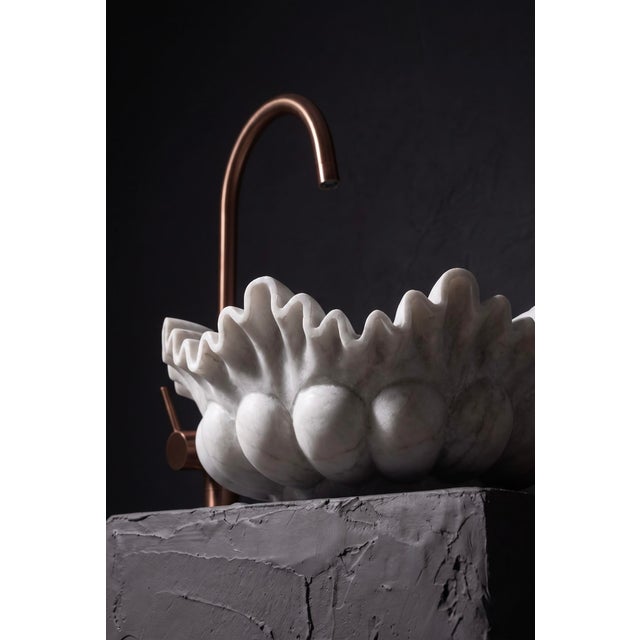 An extraordinary hand-carved vessel sink in solid Raj Nagar white marble, its scalloped rim shaped into soft, undulating...