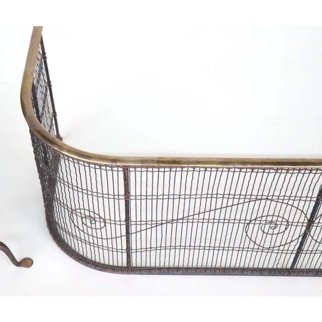An antique fireplace set consisting of a pair of iron and brass andirons with brass urn-shaped finials, brass trim at the...