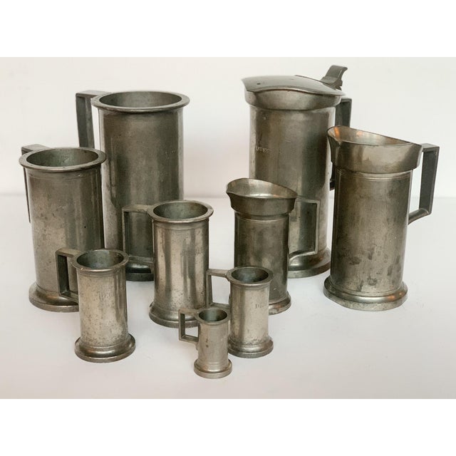 This charming mixed set of antique and vintage pewter consists of nine measuring cups made in the 19th and 20th Centuries....