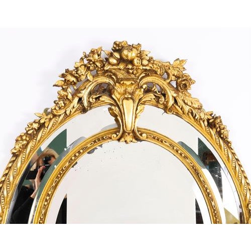 A finely carved antique Victorian oval margin plate giltwood mirror, circa 1860 in date. The bevelled mirror plate is set...