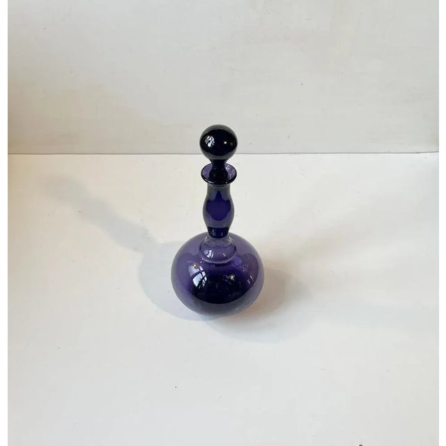 A rare purple - dark violet art glass decanter catalogued as 'No Name' in the Holmegaard Catalogue from 1958. It was...