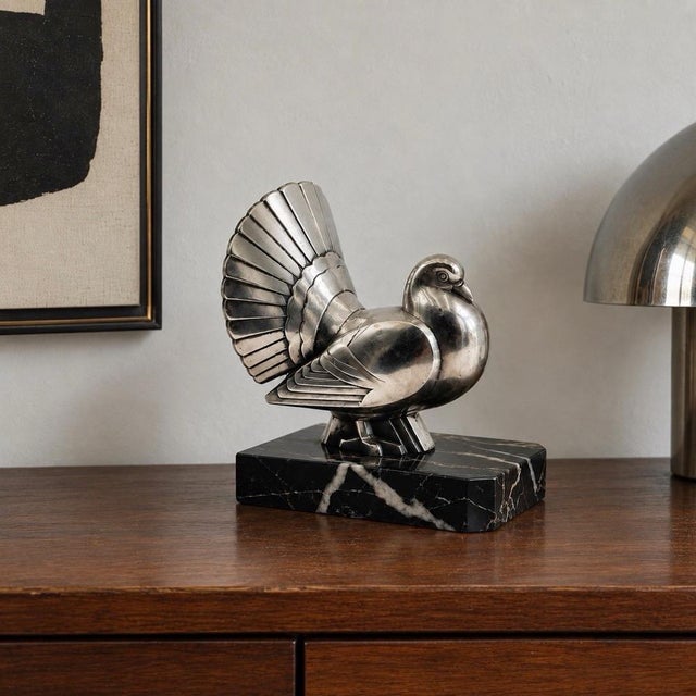 This superb freestanding sculpture depicts a "peacock-pigeon" whose silhouette is interpreted in a decidedly Art Deco...