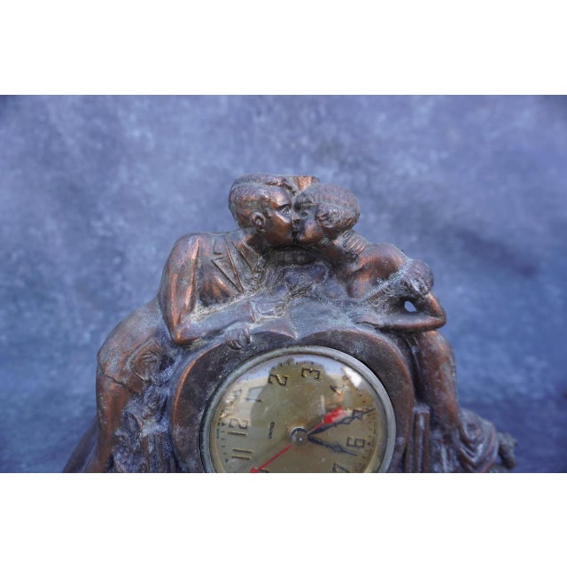 Non-working clock from United, featuring a sculptural design of two lovers, or "Sweethearts", kissing atop the clock face....