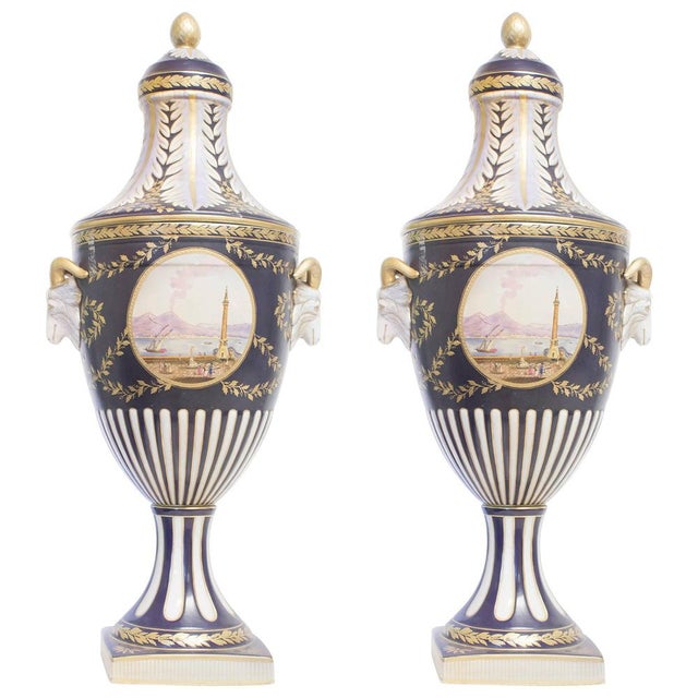 Couple of big amphoras with lids. Ceramic painted in white, blue and gold. Landscape on the front.