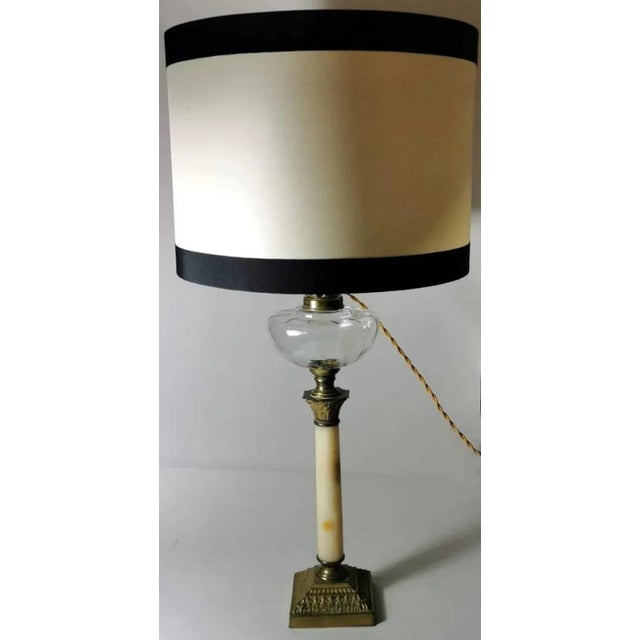 Empire style table lamp in the shape of a column; the body is in refined Afyon Miele marble from Carrara; the Corinthian...